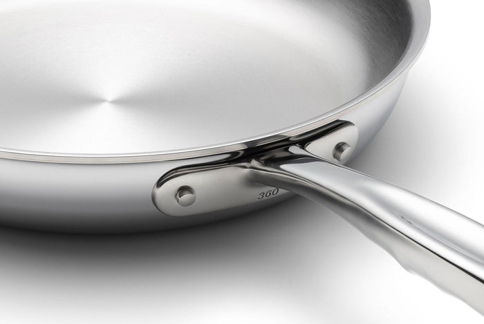 Stainless-steel frying pan close-up showing interior and riveted handle connection