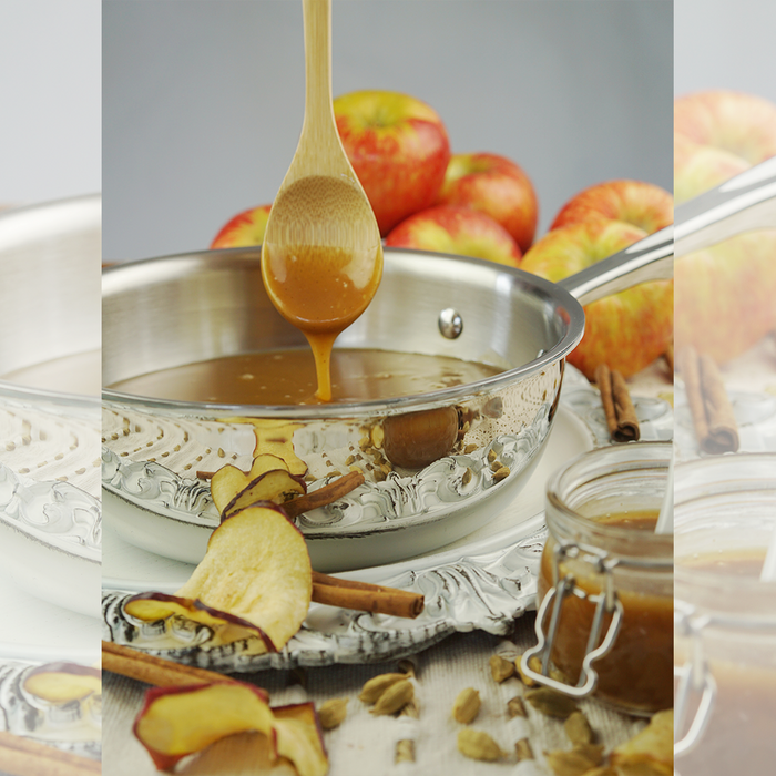 Angled view of 2 quart stainless steel saucier with rounded sides and wide mouth, caramel being poured from a wooden spoon