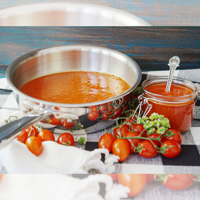 Front view of 2-quart stainless steel saucier filled with tomato sauce, showing rounded sides, flared rim, and long handle