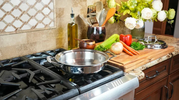 Three-quarter view of 2.3-quart stainless steel casserole with cover showing polished finish and loop handles on gas stove
