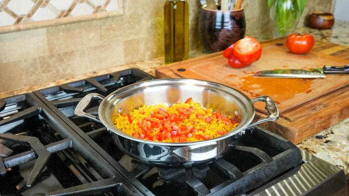 2.3-quart stainless steel casserole on gas stovetop with rice and diced tomatoes, cutting board and knife on counter