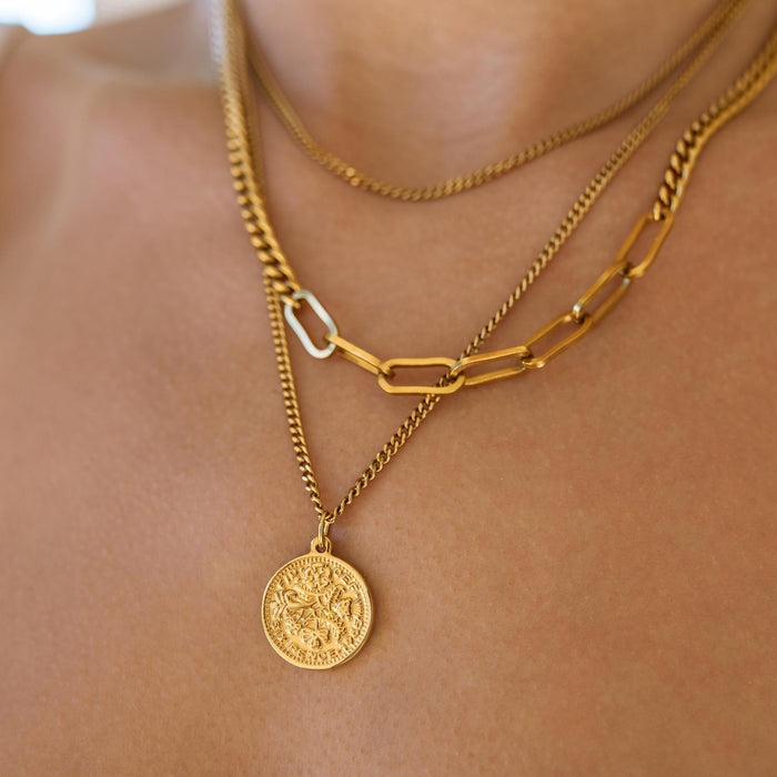 close up of a gold coin pendant with detailed designs