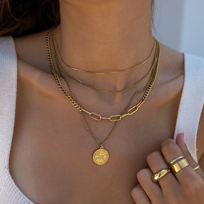 Close-up of a person wearing multiple gold necklaces and rings.