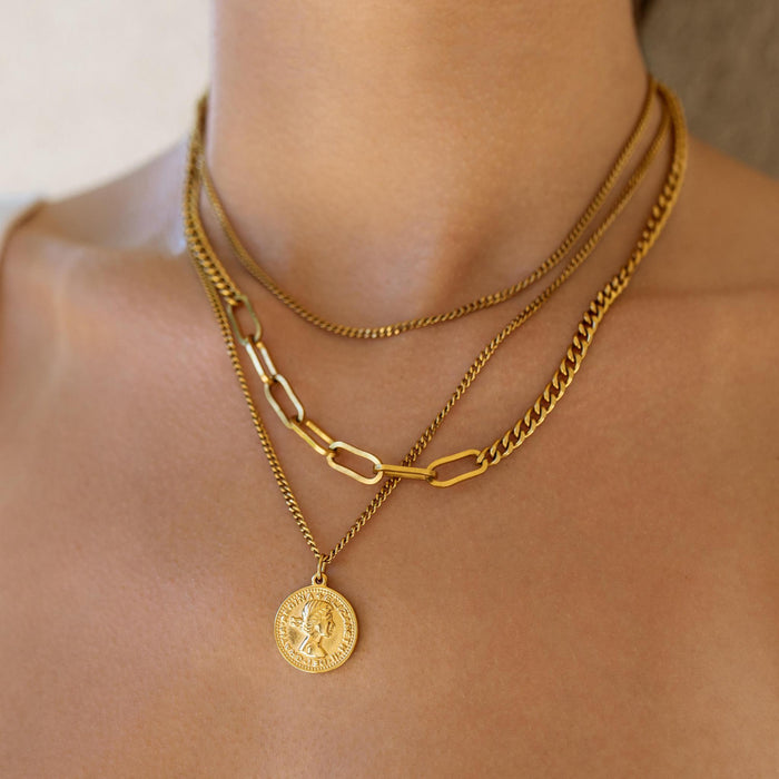close up of a layered gold necklace featuring a queen elizabeth coin pendant