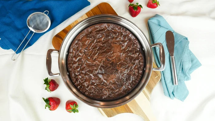 Top-down view of 3.5 quart sauté pan with short handles showing stainless steel finish and a baked chocolate dessert on a wooden board