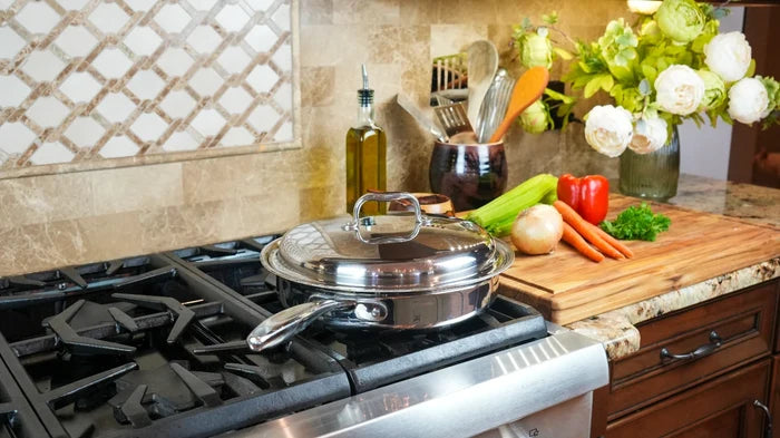 Stainless steel 3.5-quart sauté pan with lid sitting on a gas stove next to a cutting board with vegetables in a kitchen