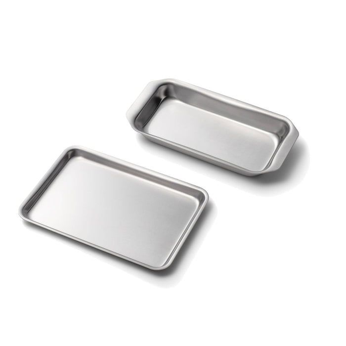 Angled view of two stainless steel mini loaf and jelly roll pans with rolled edges and smooth finish on white background