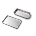 Angled view of two stainless steel mini loaf and jelly roll pans with rolled edges and smooth finish on white background