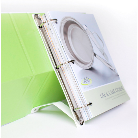 Green three-ring binder open to a page titled "360 COOKWARE USE & CARE GUIDE" showing a stainless pan photo.