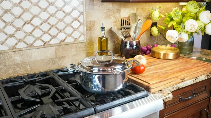 Front view of 4 Quart Stockpot with cover showcasing polished stainless-steel finish and side handles on a gas stovetop