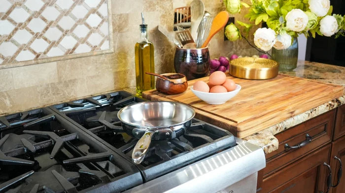 7-inch stainless steel fry pan on a gas stove next to a wooden cutting board with a bowl of eggs and utensils