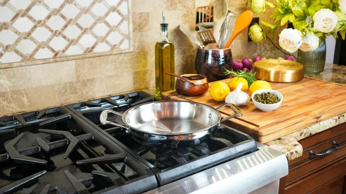 Three-quarter view of 8.5 Inch Fry Pan with Short Handles showing polished stainless interior and loop handles on a gas stove