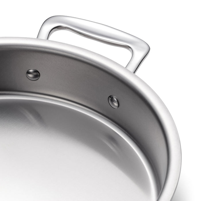 Angled close-up of 9-inch round stainless steel cake pan showcasing riveted handle and rolled rim on white background