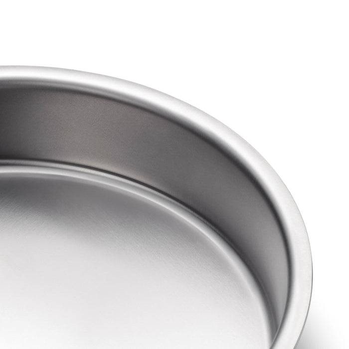 Close-up of 9-inch round cake pan showcasing rolled rim and brushed stainless-steel interior on white background