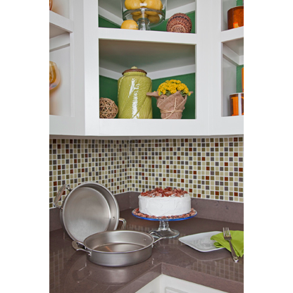 Stainless steel 9-inch round cake pan with handles displayed open on a kitchen countertop next to a frosted cake on a glass stand