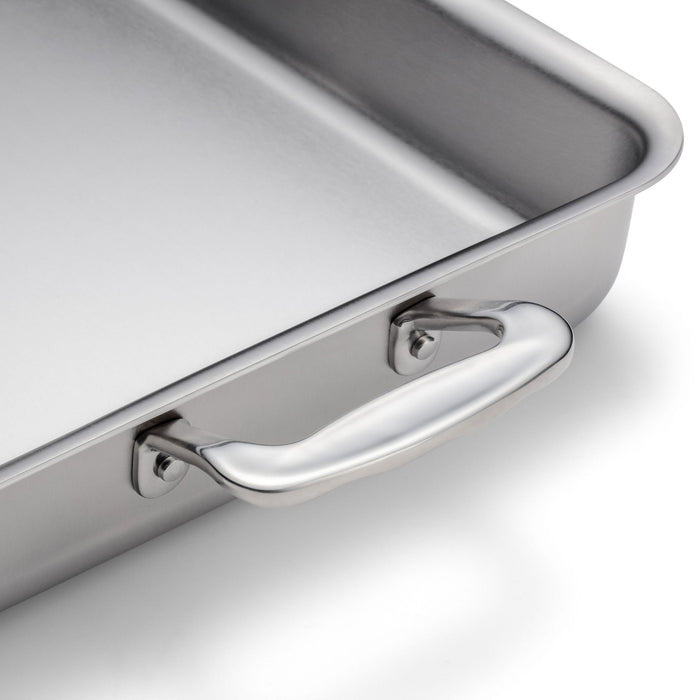 Close-up of 9x13-inch stainless steel bake and roast pan showing polished side handle on white background