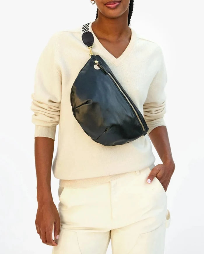 Person wearing a white sweater and pants with a black fanny pack on a white background