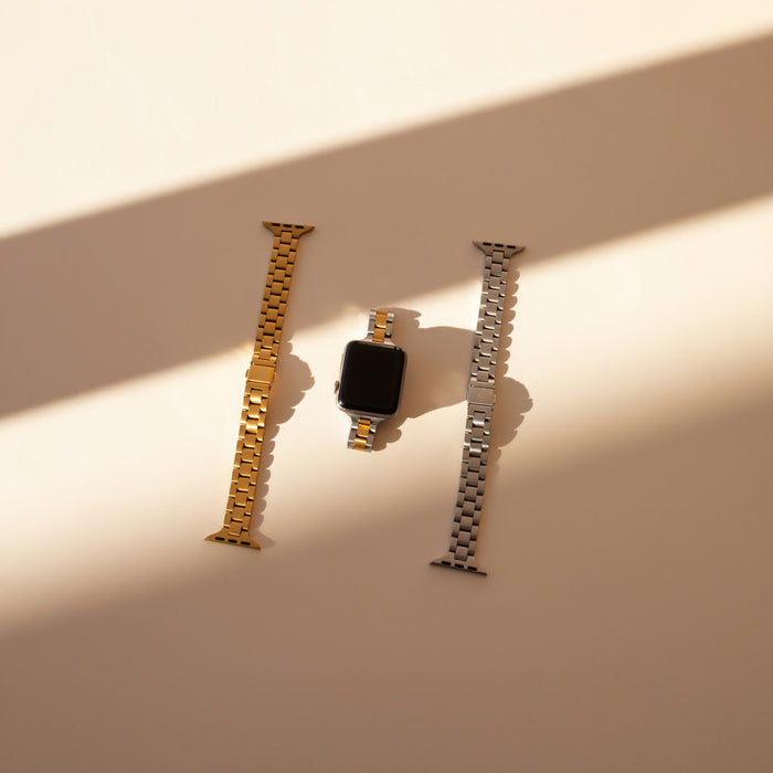 Apple watch with gold, silver, and mixed metal bands on a beige surface