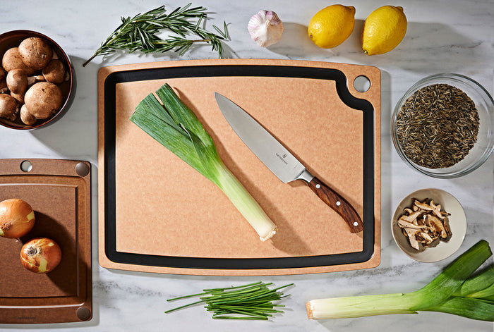 Top view of All Natural Slate Cutting Board with slate juice groove and corner hole, knife and produce on marble surface