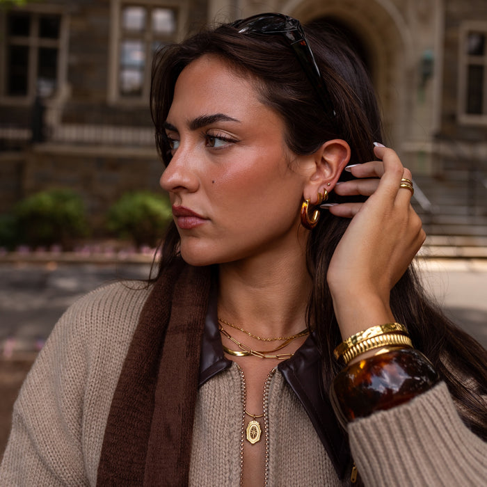 Woman adjusting her amber earring with a historic building in the background