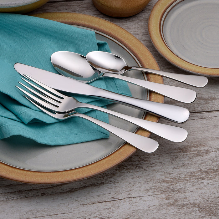 Top view of Annapolis flatware showcasing mirror-polished 18-10 stainless steel on a teal napkin and ceramic plate