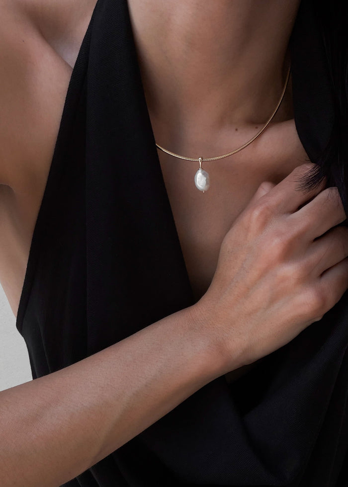 woman in a black top wearing a Kinn 14k gold Baroque Pearl Pendant on an Heirloom Curved Chain Necklace