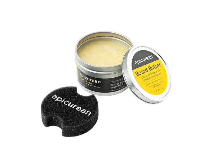 Tin of epicurean Board Butter with black epicurean sponge applicator, open to show pale yellow balm.