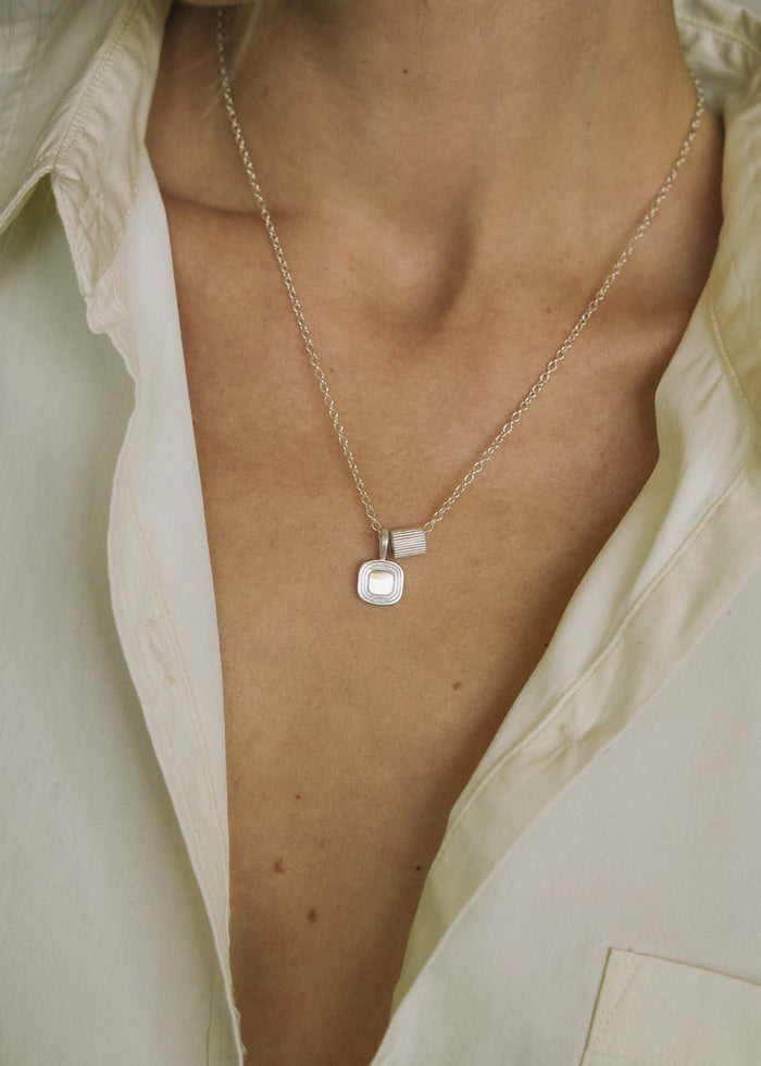 close up of a woman wearing a Kinn x Shoppe Amber Interiors The Estate Pendant Necklace in Sterling Silver with The Estate Charm Sterling Silver