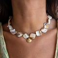 baroque pearl necklace with a gold shell pendant on a person's neck