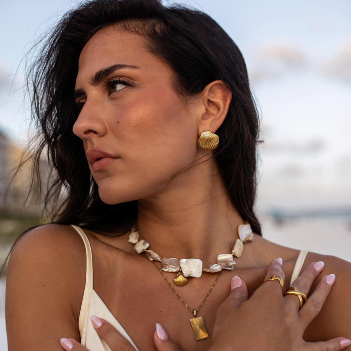A woman on vacation at the beach wearing pearl and shell gold jewelry made for the water by ALCO Jewelry