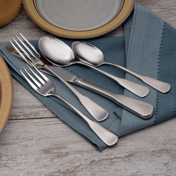 Candra flatware close-up of forks, spoons, and knife with brushed handles and mirror bowls on blue napkin, wood background
