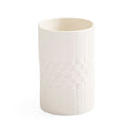 A white ceramic cup with a textured vertical ribbed pattern and a central honeycomb-like circular design, shown on a plain white background.