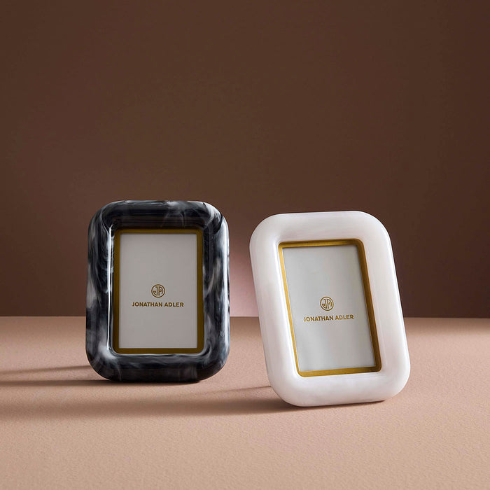 Two photo frames, one black and one white, with gold accents on a brown background.