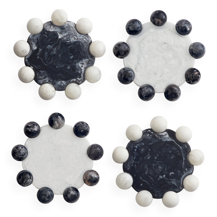 Four round decorative coasters arranged in a 2x2 grid on a white background. Each coaster features a central marbled stone disc in black, white, or dark gray tones, surrounded by a ring of smooth spherical beads in white and dark gray.