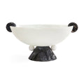 A sculptural bowl with a matte white interior and a dark, textured black exterior, featuring spherical side handles and a pedestal base on a white background.
