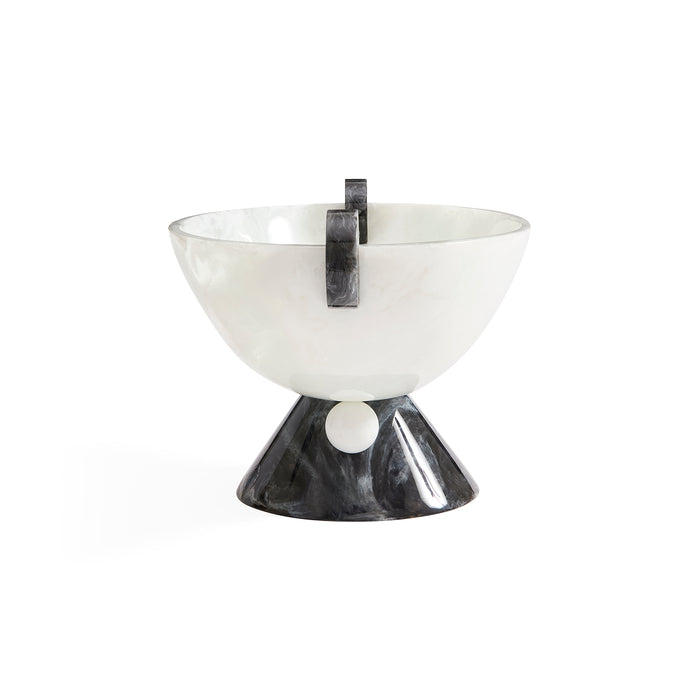 A modern sculptural bowl with a glossy white marbled upper bowl and a contrasting glossy black marbled base, featuring a vertical black metal loop handle and a small white circular accent on the front.