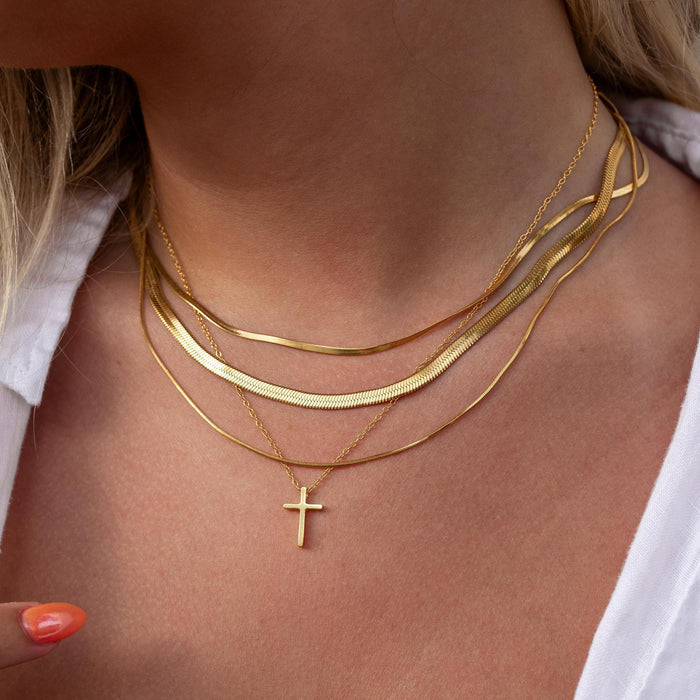 simple everyday necklace stack with thin gold herringbone chains and a delicate cross necklace