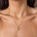 A dainty gold necklace with a geometric circle pendant worn by a woman.