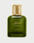 A green glass bottle of EARTHA EAU DE PARFUM by Harlem Perfume Co., featuring a gold textured cap and label with gold script, embodies fearless sophistication—shown against a white background.