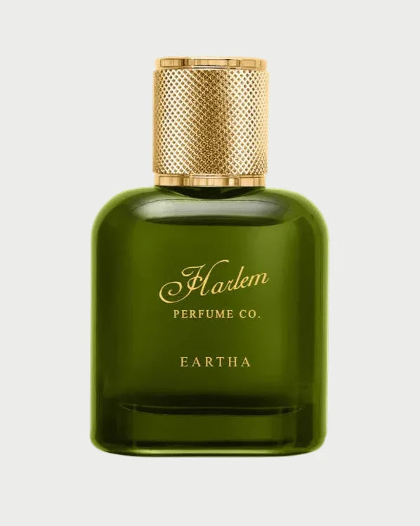 A green glass bottle of EARTHA EAU DE PARFUM by Harlem Perfume Co., featuring a gold textured cap and label with gold script, embodies fearless sophistication—shown against a white background.
