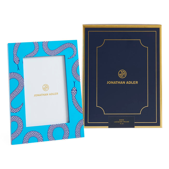 Two Jonathan Adler picture frames, one blue with a snake pattern and the other navy with gold text, on a white background.