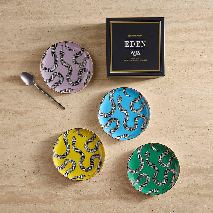 Set of four colorful ceramic plates with snake patterns on a wooden surface, accompanied by a box labeled 'Eden'.