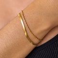 A double layer gold bracelet on a person's wrist, showing a chain link design.