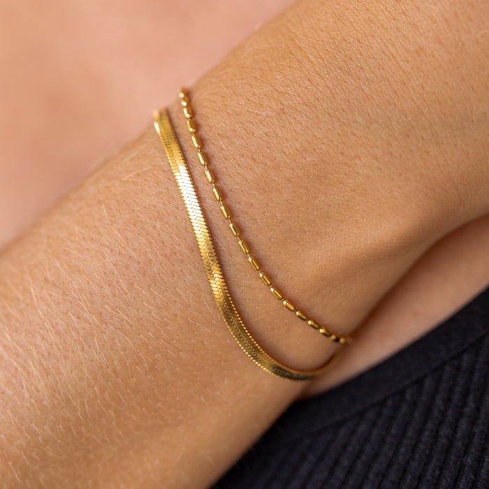 A double layer gold bracelet on a person's wrist, showing a chain link design.