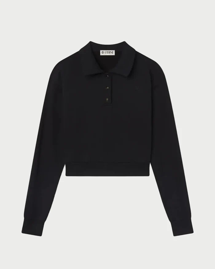 The Éterne Cropped Polo Sweatshirt by Eterne is a black, long-sleeve cropped sweatshirt featuring a collar and three buttons at the top. Crafted from soft French terry for a relaxed fit, it is displayed on a white background.