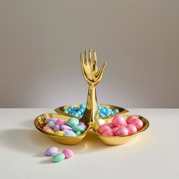 Gold fork and spoon-shaped dish with colorful candies on a neutral background