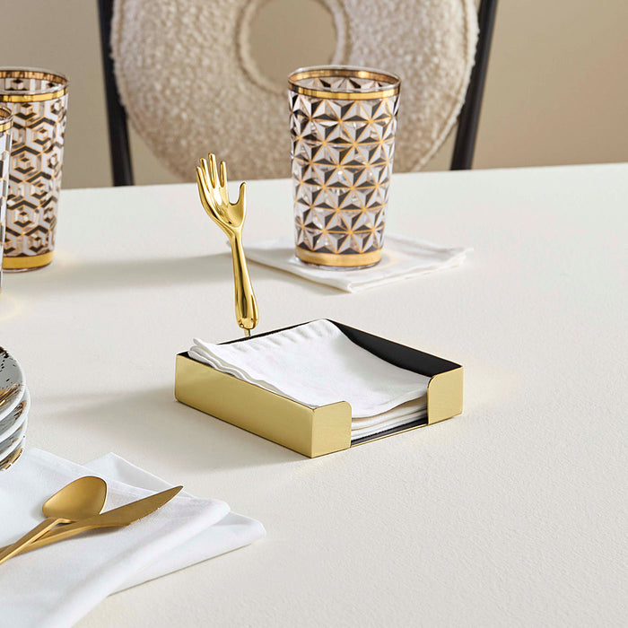 Dining table setting with gold cutlery, geometric-patterned glasses, and a napkin holder.