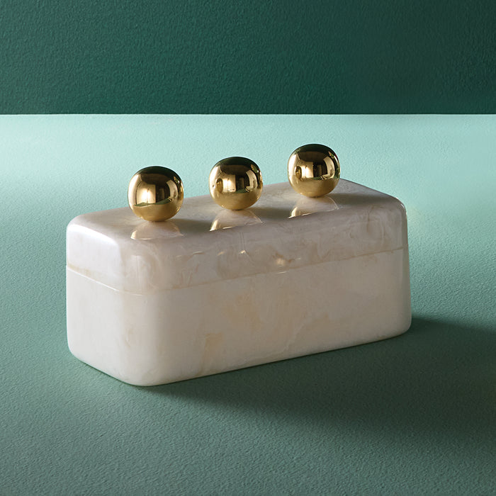 Rectangular white marble box with three gold spherical knobs on a teal background