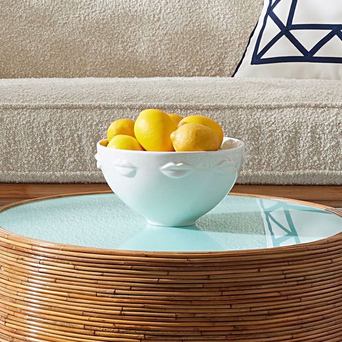 Bowl of lemons on a glass-top coffee table with a textured sofa in the background