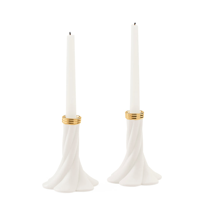 A pair of white taper candle holders with a flared, sculptural base and gold metallic bands near the top, shown on a plain white background.